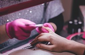 Nail technician painting women's nails.